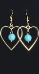 Gold color heart shape metal loops with a turquoise color bead hanging in the middle of each.