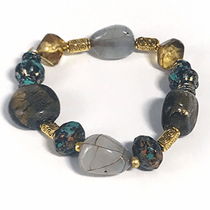 Stretchable bracelet of mixed brown beads, and turqoise and black specked beads, a two light grey color bead with brown cracked mesh pattern, and long gold color separators.